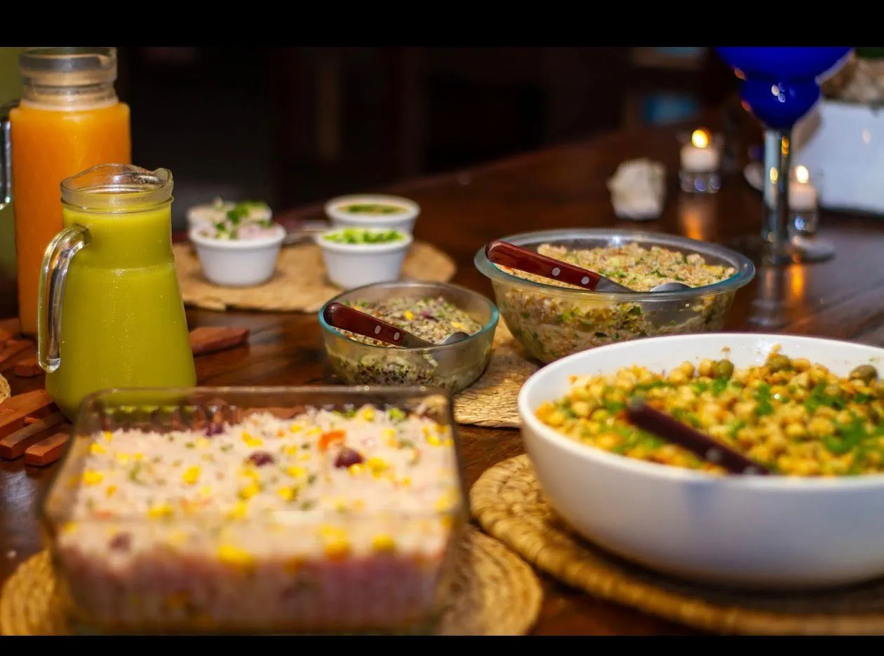 Cena con bowls de granos, ensaladas y jugos en mesa de madera