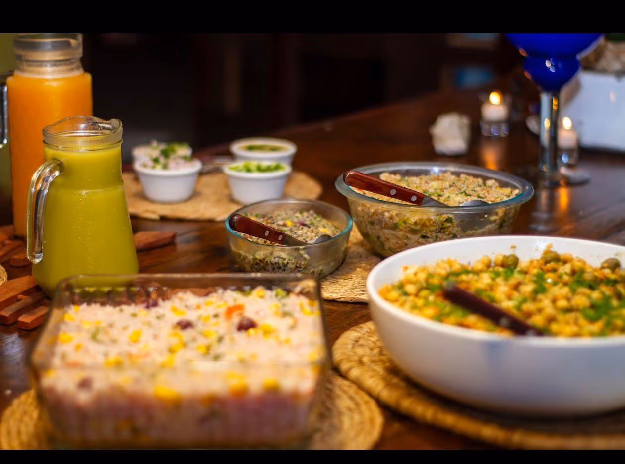 Cena con bowls de granos, ensaladas y jugos en mesa de madera