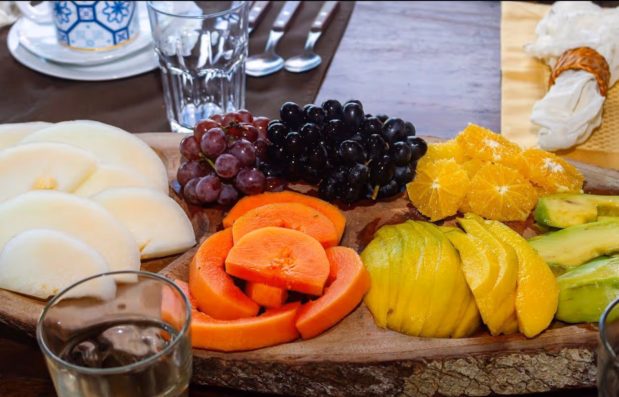 Tabla de uvas, papaya, mango y palta servida en madera