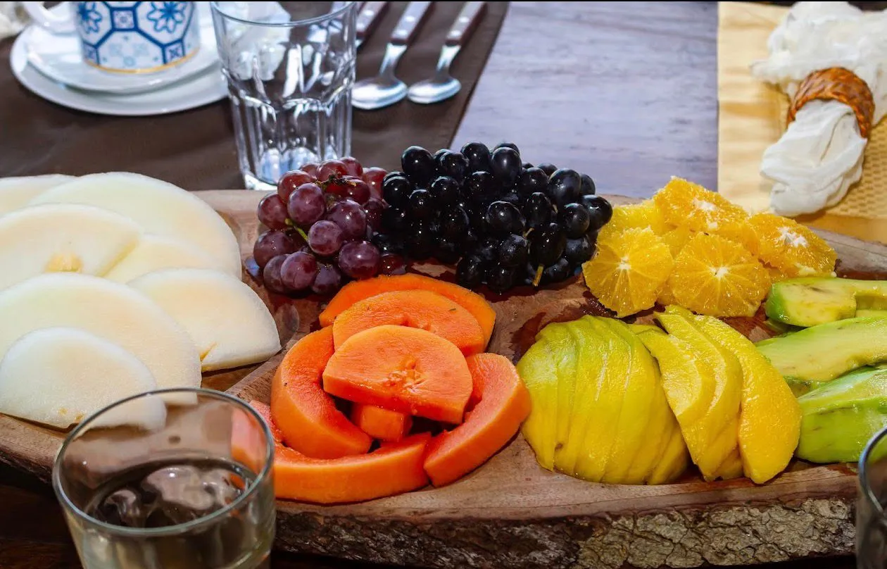 Tabla de uvas, papaya, mango y palta servida en madera