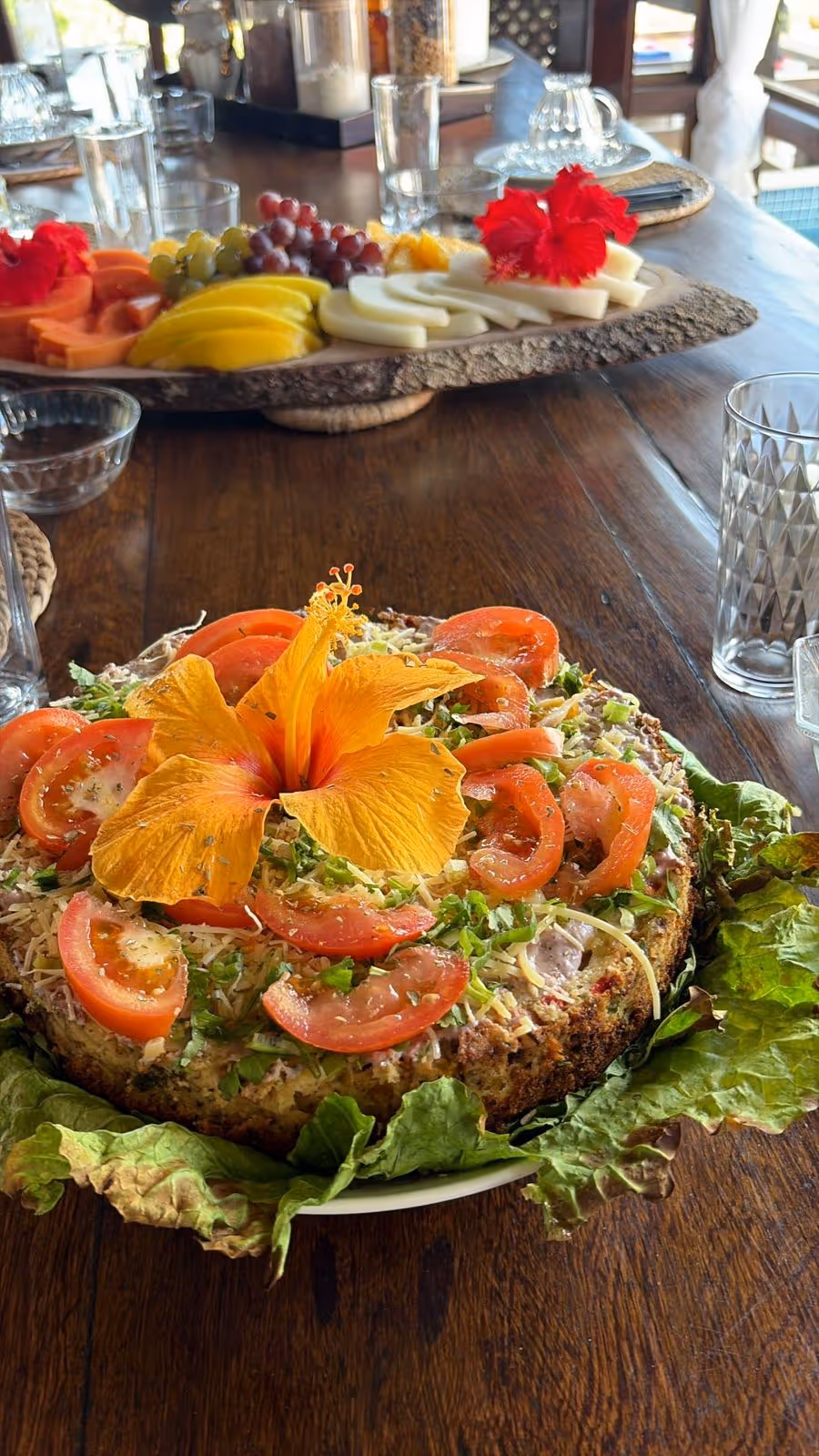 Torta salada decorada con tomates y flor de hibisco anaranjada