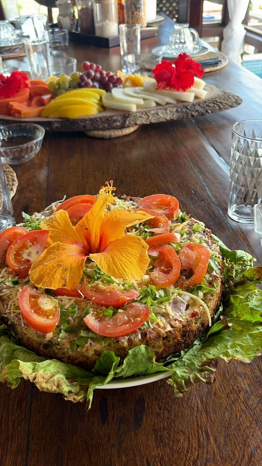 Torta salada decorada con tomates y flor de hibisco anaranjada
