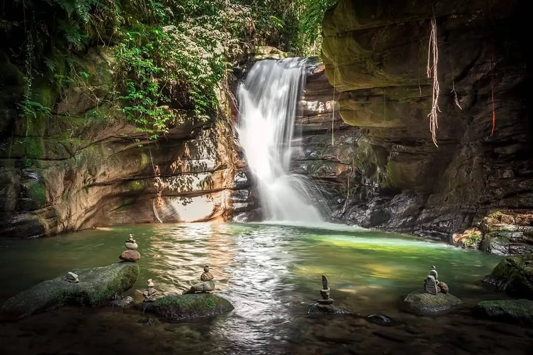 Cascada entre rocas y vegetación en Sana